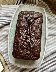 a loaf of chocolate cake sitting on top of a white plate