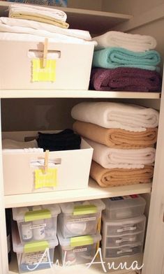 an organized closet filled with folded towels and other items, including bins for storage