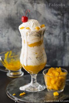 an ice cream sundae in a glass with mango slices on the rim and a cherry garnish