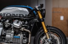 a blue and silver motorcycle parked in front of a garage door with the word honda on it's side