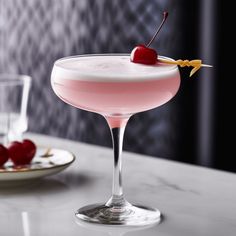 a pink drink with a cherry garnish on the rim