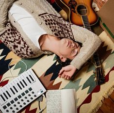 a man laying on top of a rug next to a guitar