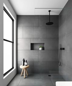 a modern bathroom with gray walls and tile flooring, along with a round table in front of the shower