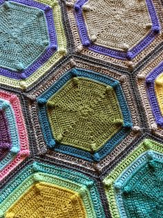 a multicolored crocheted afghan with hexagons in the middle