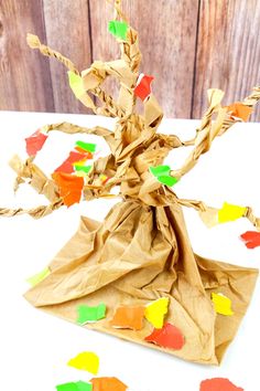 an origami tree made out of brown paper and colored stickers on it