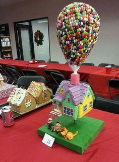 a table topped with lots of candy covered houses and balloons in the shape of houses