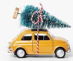 a small yellow car with a christmas tree on it's roof and candy canes in the trunk