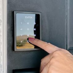 a person pressing the button on an electronic door lock with their thumb and index finger