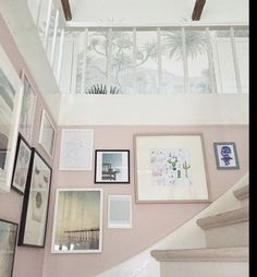 the stairs are covered with pictures and framed photographs on pink walls, along with white railings