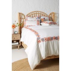 a bed with an orange and white bedspread on it's headboard