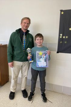 an older man and young boy standing next to each other holding trophies in their hands