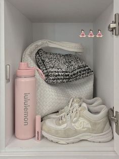 a pink water bottle sitting on top of a white shelf next to a pair of sneakers