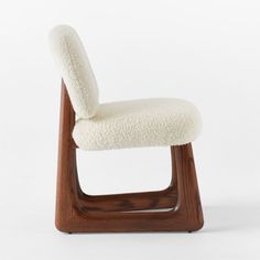 a white chair with a wooden frame and sheep fur on it's backrest