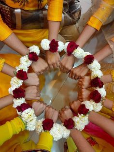 several people are holding hands in a circle with flowers on the bottom and one is wearing yellow