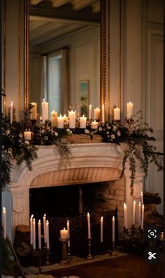 a mantel with candles and greenery on it