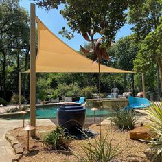 an outdoor area with a pool, water feature and shade sail in the middle of it