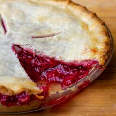 a pie with a piece missing from it sitting on a wooden table next to a knife