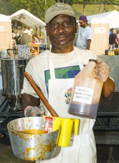 a man in an apron holding a bottle and mixing bowl