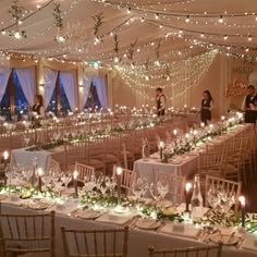 the tables are set up for an event with candles and greenery on each table