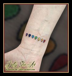 a person's hand with a small rainbow tattoo on the left side of their wrist