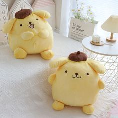 two yellow stuffed animals sitting on top of a white bed next to a lamp and table