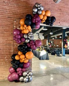 an arch made out of balloons in the middle of a room with tables and chairs