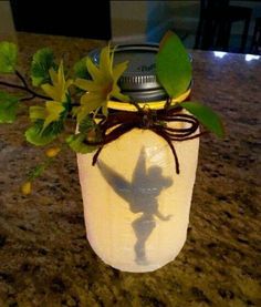 a mason jar with leaves and a bird on the lid is sitting on a counter