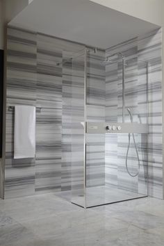 a bathroom with a walk in shower next to a white towel hanging on the wall