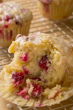 a muffin with white frosting and cranberry toppings on a cooling rack