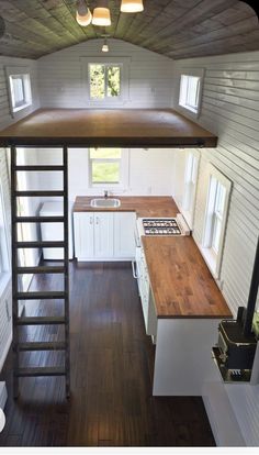 the interior of a tiny house with wood flooring and stairs leading up to an open kitchen area