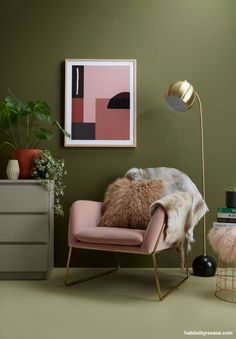 a living room with green walls, pink chair and gold floor lamp in the corner