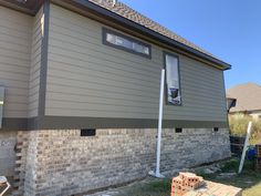 a house that is being built with brick and siding on the side of it,