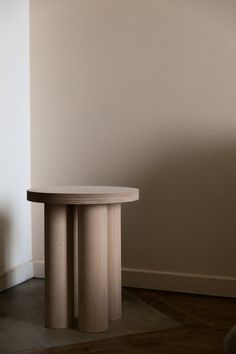 a small round table sitting on top of a hard wood floor next to a wall