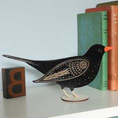 a black bird figurine sitting on top of a white shelf next to books