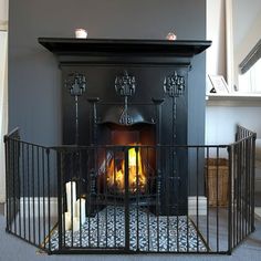 a fireplace in a living room next to a metal gate with candles on it's sides