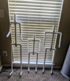 four white pipes are standing in front of a window with the blinds pulled down and wires attached to them