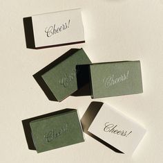 four place cards with the word cheers placed on top of each other in small boxes