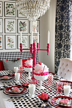 a dining room table set with black and white checkered cloths, pink candlesticks, and red plates