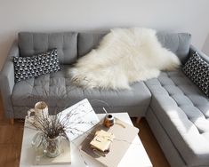 a living room with a gray couch and white pillows on the back of it's sofa