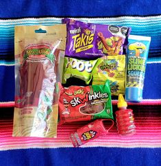 some snacks are laying out on a blue and pink blanket with a striped towel in the background