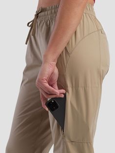 a person holding an electronic device in their right hand while wearing khaki pants