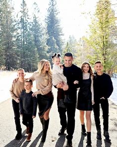 a group of people standing next to each other in front of snow covered ground and trees