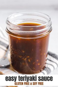 a glass jar filled with sauce sitting on top of a towel next to a spoon