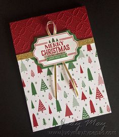 a merry christmas card with trees and snowflakes on the front, hanging from a string