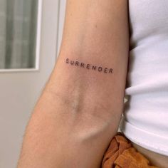 a person with a small tattoo on their arm that says,'surender '