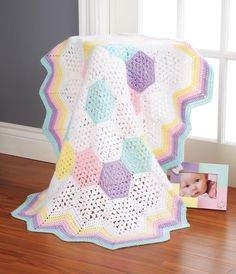 a crocheted blanket is on the floor next to a photo frame and an album