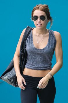 a woman in black pants and grey top carrying a handbag while walking down the street