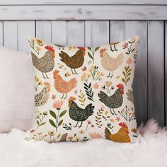 a pillow with chickens on it sitting on a white furnishing next to a wooden headboard