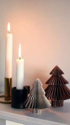 three candles sitting on top of a table next to a christmas tree and other decorations