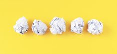 four pieces of crumpled paper lined up on a yellow background